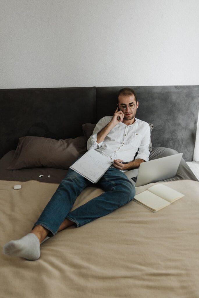 man in white dress shirt and blue denim jeans sitting on brown couch